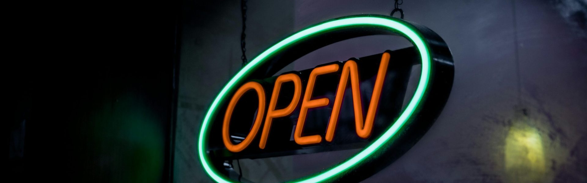 Vibrant neon open sign glowing in a dimly lit setting, creating a welcoming ambiance.